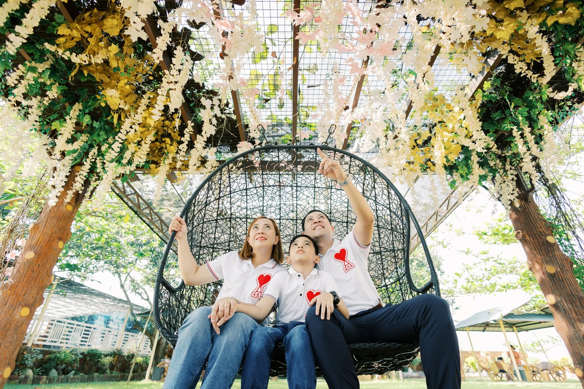 A family enjoying the garden swing beneath flowers at Family Farm Resort